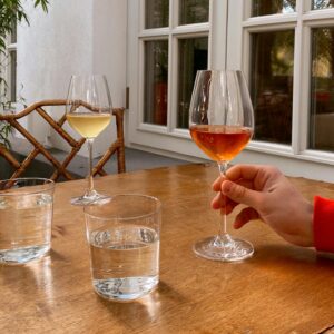 Outdoor setting with glasses of red and white wine on a wooden table.