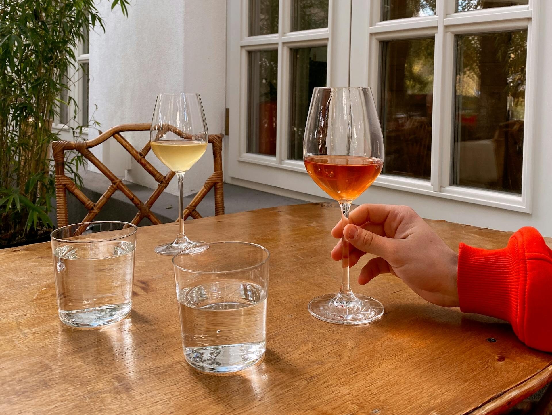 Outdoor setting with glasses of red and white wine on a wooden table.